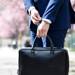 A person holding a briefcase while straightening a jacket cuff. Photo Credit: Andrea Natali on Unsplash [https://unsplash.com/photos/jdTtkmr1axk]
