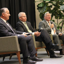 The Third Annual UT Dallas Economic Development Summit. A group of speakers sitting in chairs on a stage, engaged in a panel discussion. From left: Chris Nielsen, EVP of Product Support and chief quality officer, Toyota Motor North America; Rich Templeton, president, chairman and CEO, Texas Instruments; Dr. Richard C. Benson, president of the University.