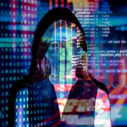 DFW Labor Market Update. A programmer lit up by a multicolored projection of her own code. Photo Credit: ThisisEngineering RAEng on Unsplash [https://unsplash.com/photos/8hgmG03spF4]