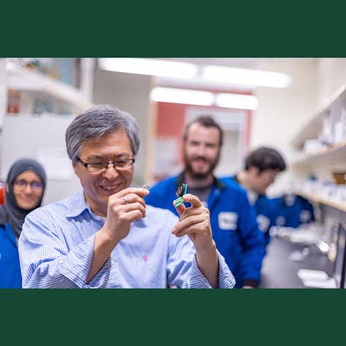Dr. Kyeongjae Cho displays a finished battery and the hardware used to test its efficiency. Working behind him, from left to right, are science and engineering doctoral students Manifa Noor and Matthew Bergschneider, and research associate Dr. Taesoon Hwang.