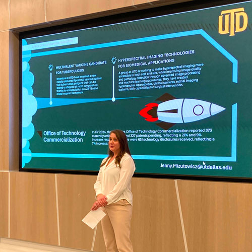 Director of Economic Development Jenny Mizutowicz makes a presentation while standing in front of a screen that describes the UT Dallas Office of Technology Comercialization.