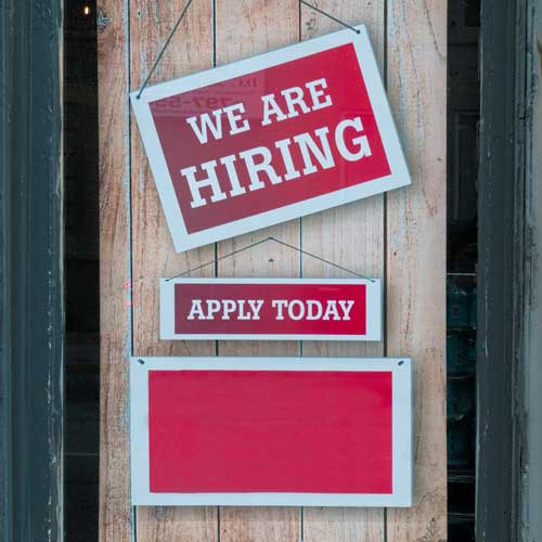 DFW Labor Market Update. A trio of red signs hanging on a door. The top one reads “WE ARE HIRING”. The next reads “APPLY TODAY”. The bottom one is blank. Photo Credit: Eric Prouzet on Unsplash [https://unsplash.com/photos/a-sign-that-says-we-are-hiring-and-apply-today-B3UFXwcVbc4]