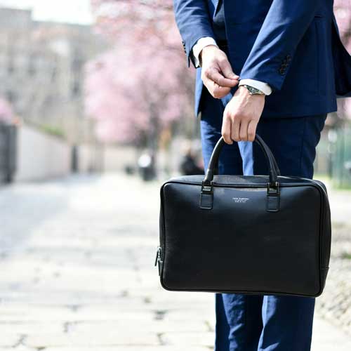 Labor Market Explorer for Students. A person holding a briefcase while straightening a jacket cuff. Photo Credit: Andrea Natali on Unsplash [https://unsplash.com/photos/man-in-blue-suit-standing-on-street-side-while-holding-bag-during-daytime-jdTtkmr1axk]