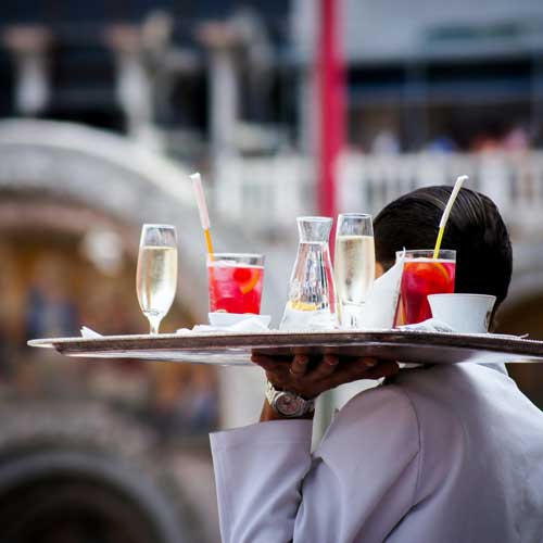 DFW Labor Market Update. A waiter carrying a tray of drinks. Photo Credit: Kate Townsend on Unsplash [https://unsplash.com/photos/waiter-serving-beverages-hEC6zxdFF0M]