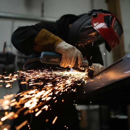 The Connection. Sparks fly as a worker grinds a piece of metal. Photo Credit: 2020 Josh Beech on Unsplash [https://unsplash.com/photos/person-in-black-jacket-holding-brown-wooden-rolling-pin-tXJhAFVOHVk]