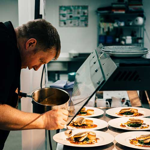 The Connection. A chef spooning sauce onto dishes of food. Photo Credit: 2020 Sebastian Coman Photography on Unsplash [https://unsplash.com/photos/man-in-black-t-shirt-holding-stainless-steel-bowl-eBmyH7oO5wY]