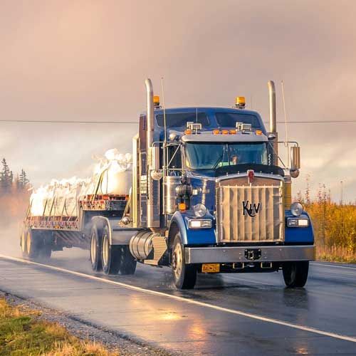 DFW Labor Market Update. A semi trailer truck traveling through the countryside. Photo Credit: 2020 Zetong Li on Unsplash [https://unsplash.com/photos/white-and-blue-truck-on-road-during-daytime-mVqTumQH-c0]