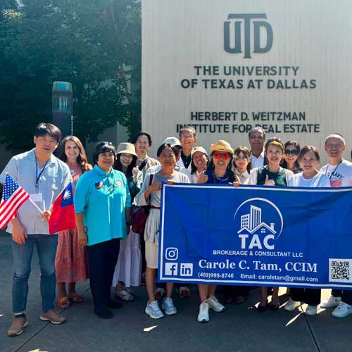 A group of people pose for a photo on the UT Dallas campus in front of a sign that reads “UTD, The University of Texas at Dallas, Herbert D. Weitzman Institute for Real Estate”.